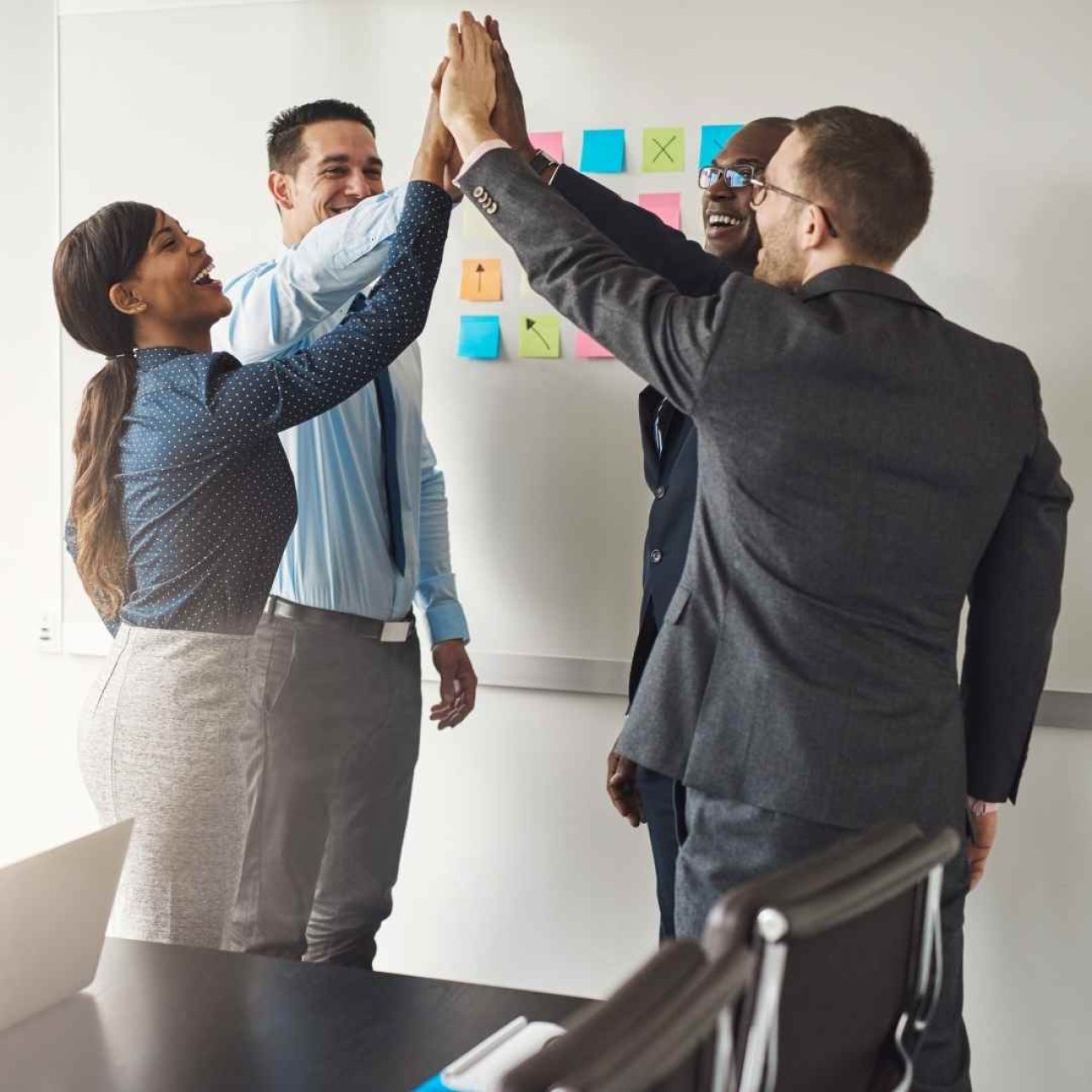 A group of people high fiving with smiles.