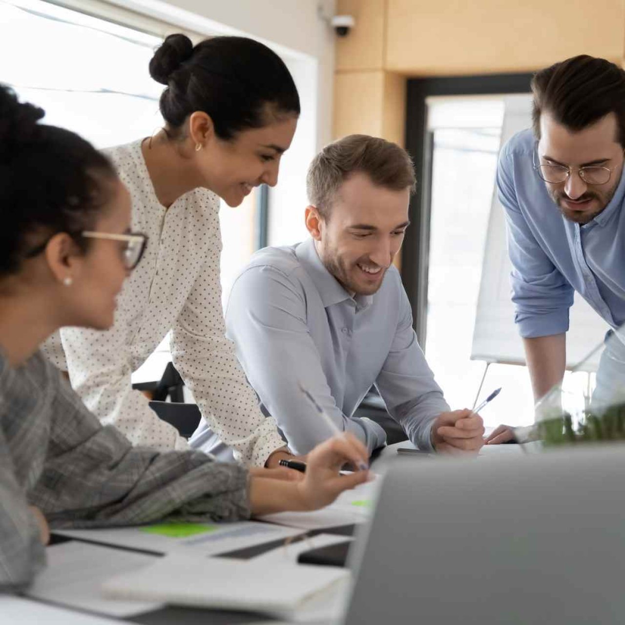 How are your team doing with their professional relationships? 4 people sat around a desk writing and collaborating.